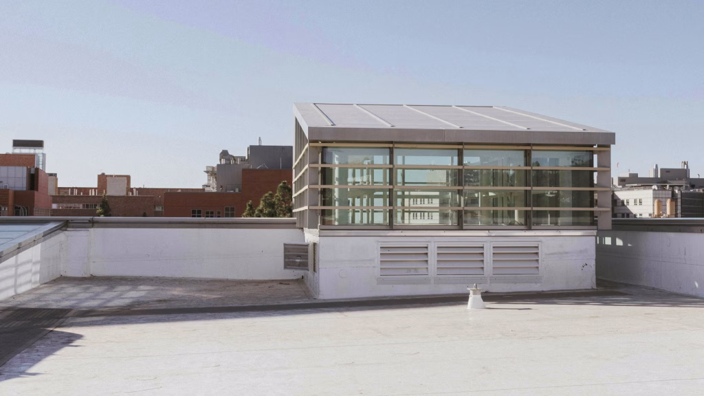 Commercial flat roof with a modern glass rooftop addition and solar panels.