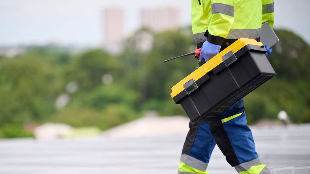 Worker holding a toolbox and inspecting a rooftop