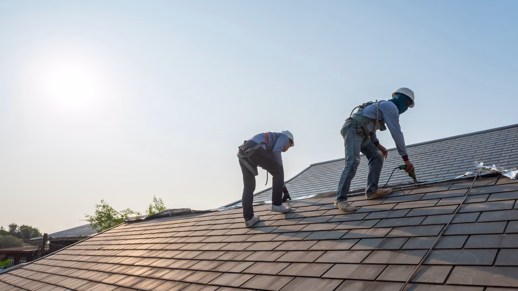 Roofer working in special protective work wear gloves, using air or pneumatic nail gun repair and replace roofing tiles on top of the new roof under construction residential building