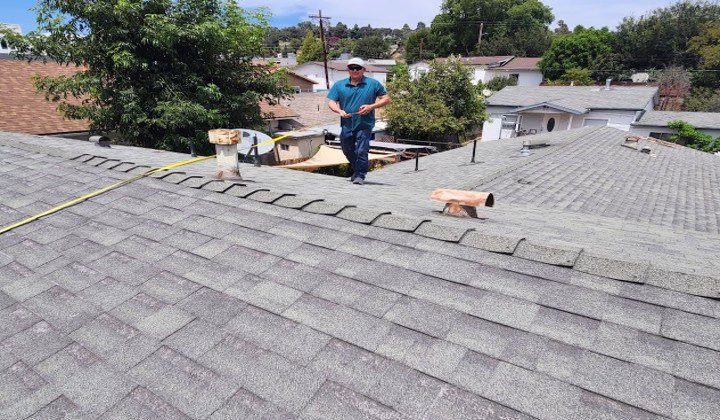 CrownLine Roofing Tech performing an inspection on an aging asphalt shingle roof to evaluate overall roof condition and identify maintenance or repair needs.